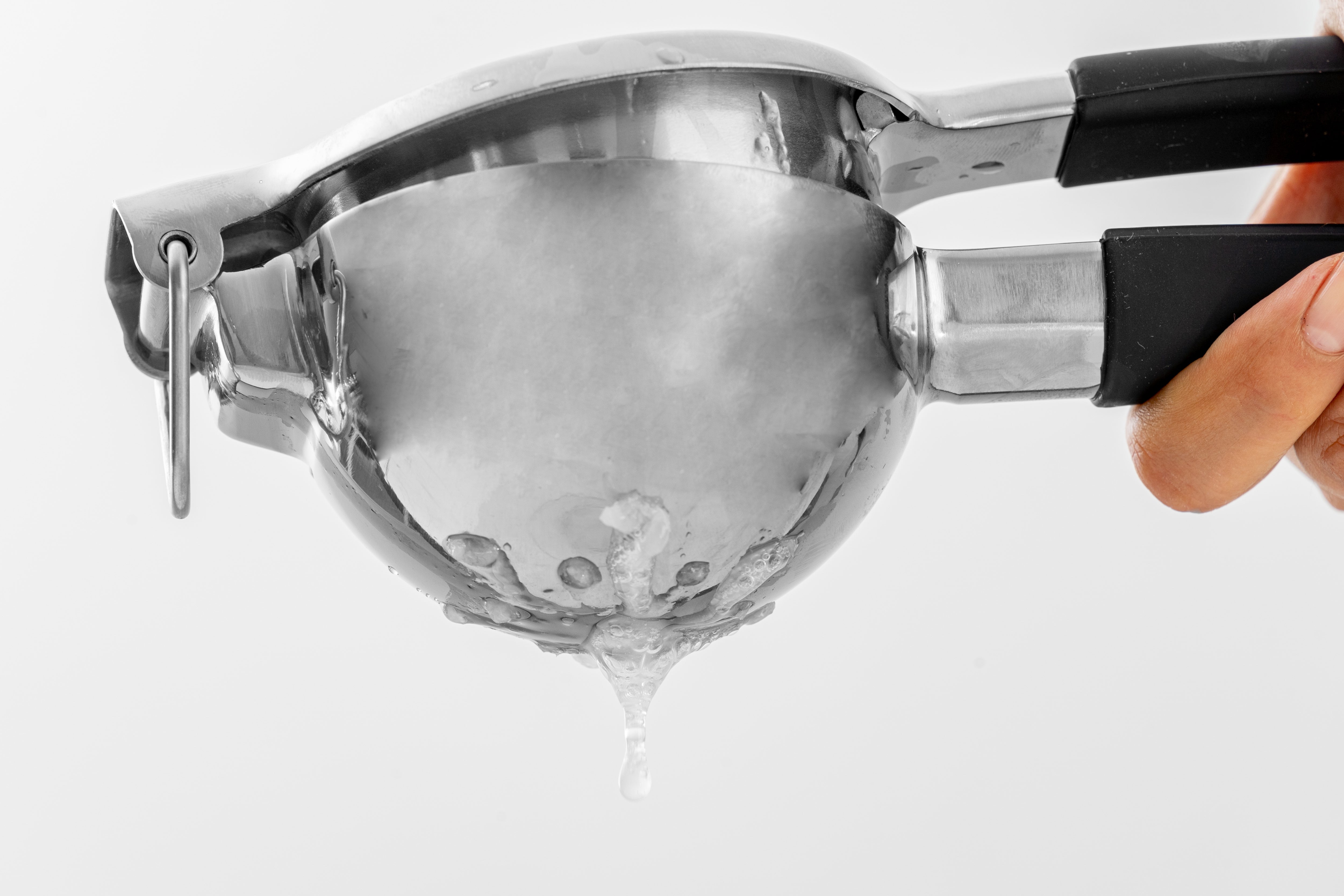 Stainless steel citrus juicer squeezing fresh lemon juice on white background