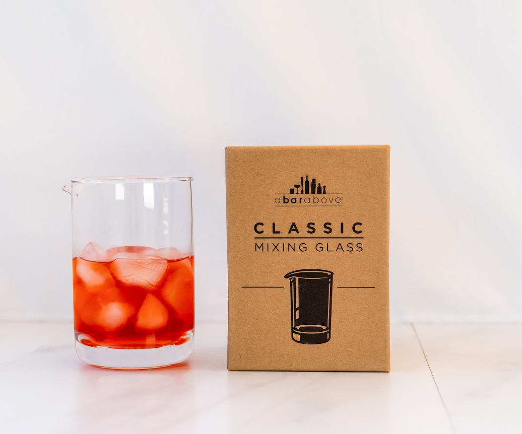 Cocktail mixing glass with a red cocktail and ice inside, next to its gift box reading "Classic Mixing Glass," set against a white backdrop