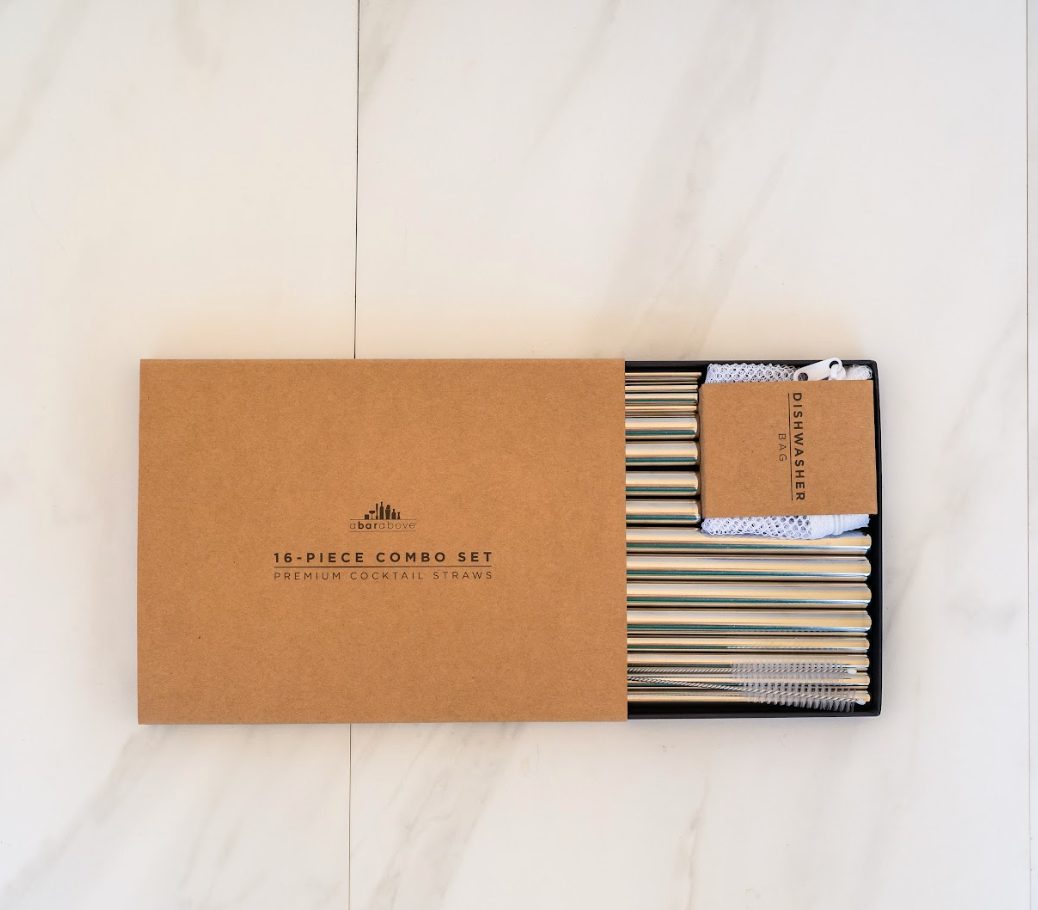 Flatlay photo of a half-open rectangular gift box on a white marble table, opened to reveal a pack of 12 stainless steel drinking straws