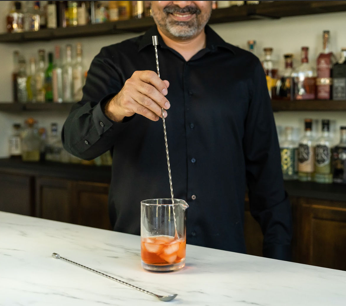 Bartender stirring a cocktail in a mixing glass with an stainless steel extra-long bar spoon with spiral handle