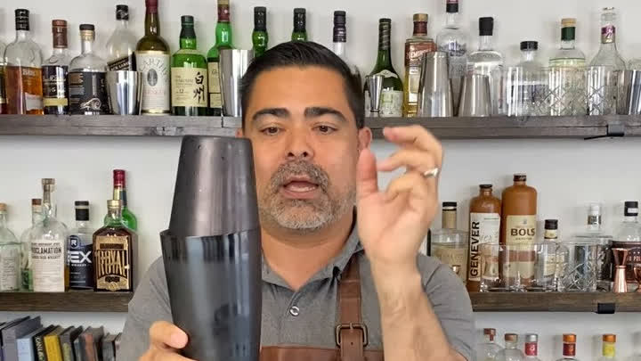 Bartender demonstrating a Boston shaker technique at the bar